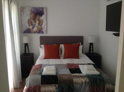 a bedroom with a bed with a painting on the wall at Sikelela Guest House in Cape Town