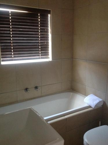 a bathroom with a tub and a toilet and a window at Sikelela Guest House in Cape Town