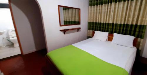 um quarto com uma cama verde e branca e um espelho em Fallside Rest em Norton Bridge