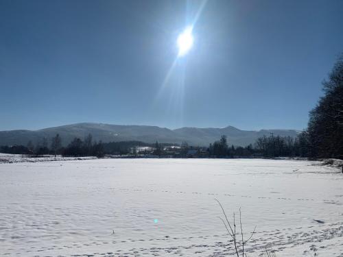 a snow covered field with the sun in the sky at Sarnia Polana in Kostrzyca