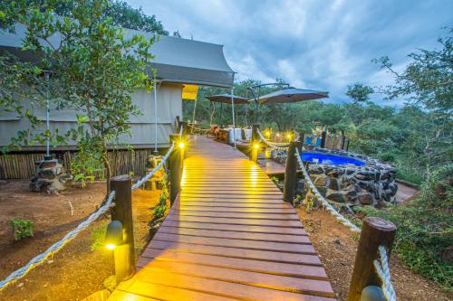 a wooden walkway leading to a building with lights at Mountain View Safari Lodge in Hoedspruit