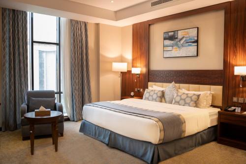 um quarto de hotel com uma cama e uma cadeira em Seasons Park- mawasim al hay at hotel em Jeddah