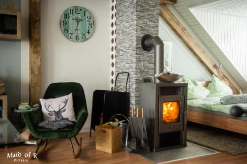 a living room with a wood stove and a bed at Hof Vierzehnender im Hohen Venn - 70qm Fachwerk-Studio - grosses Wohn-Schlafzimmer mit Dachterrasse und Kaminofen - separate Küche - perfekt für Paare - Monschau - Eifel - Hunde willkommen - Islandpferde in Monschau