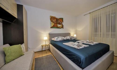 a bedroom with a blue bed and a couch at Apartments Bolero in Rab