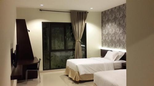 a hotel room with two beds and a window at White Rock Lodge in Nusa Dua