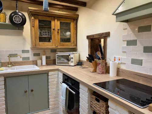 eine Küche mit einer Theke mit einer Spüle und einer Mikrowelle in der Unterkunft Rock View Cottage, 2 bedrooms near Alton Towers in Alton