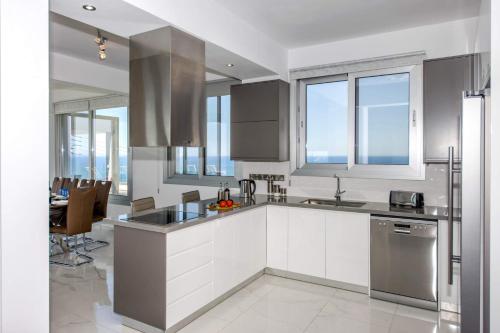 una cocina con armarios blancos y electrodomésticos de acero inoxidable en Elite Sea View Villa, en Pomos