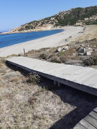 a wooden boardwalk on the side of a beach at casa rosa nel residence mirice con piscina ,wifi,climatizzatore - vicino al mare in Aglientu