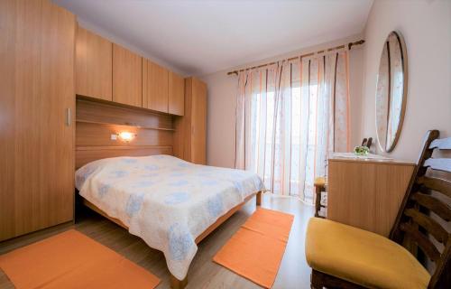 a bedroom with a bed and a chair and a window at App&Rooms Anica Kampor in Kampor