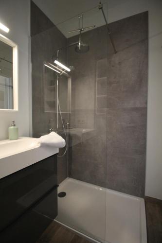 een badkamer met een glazen douche en een wastafel bij Zeewende 18 in Zeebrugge
