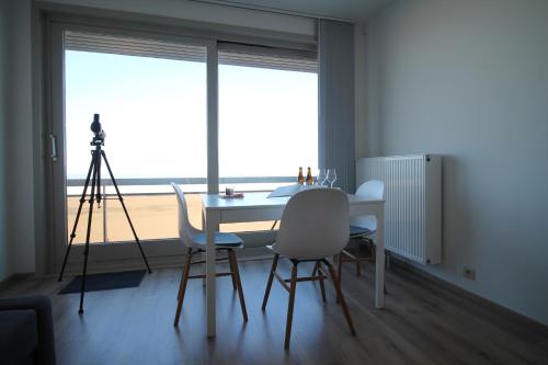 een eetkamer met een tafel en stoelen en een camera bij Zeewende 18 in Zeebrugge