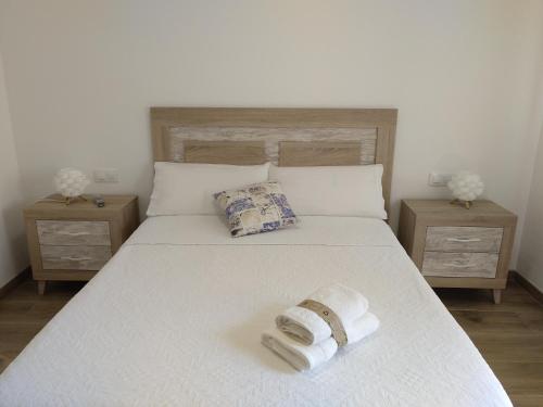 a bed with two towels on it with two night stands at Alojamiento Lo Trabucador in El Poblenou del Delta