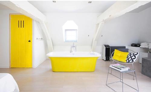 La salle de bains est pourvue d'une grande baignoire jaune. dans l'établissement Maison Mathilde, à Valenciennes