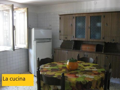 a kitchen with a table and a refrigerator at Torre Ovo, Salento, casa in riva allo Jonio in Torre Ovo
