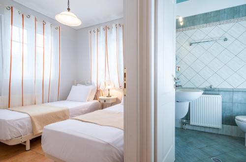 a room with two beds and a bathroom with a sink at Meganisi Villas in Spartokhórion