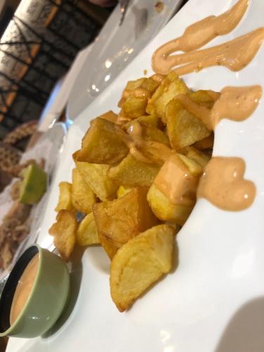a white plate topped with potato chips and sauce at Picasso City Center 1A in Málaga