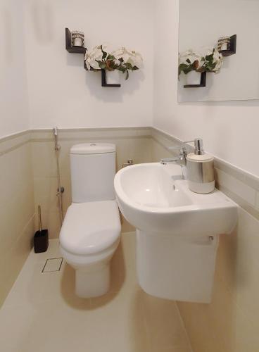 a white bathroom with a toilet and a sink at Spacious 2 Bedroom Apartment DXB in Dubai