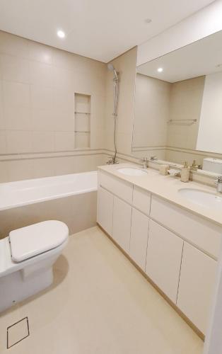 a white bathroom with a toilet and a sink at Spacious 2 Bedroom Apartment DXB in Dubai