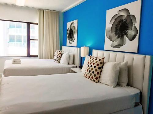 two beds in a room with blue walls at Miami BeachFront with Pool WIFI & Cheap parking in Miami Beach