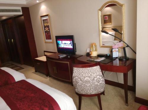 a hotel room with a desk with a computer and a mirror at Dynasty International Hotel Dalian in Jinzhou