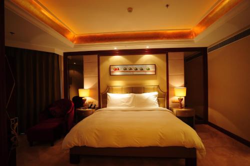 a bedroom with a large bed and two lamps at Dynasty International Hotel Dalian in Jinzhou