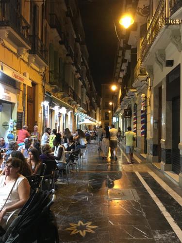 a group of people sitting in chairs on a street at night at Picasso City Center 1A in Málaga