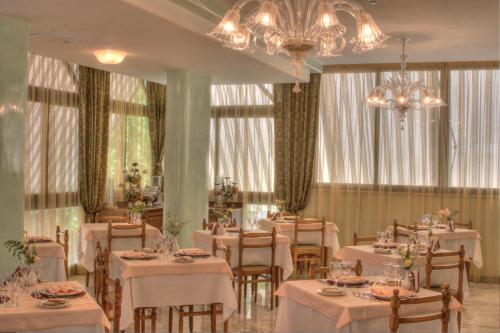 a dining room with white tables and chairs and chandeliers at Hotel Hamilton in Misano Adriatico