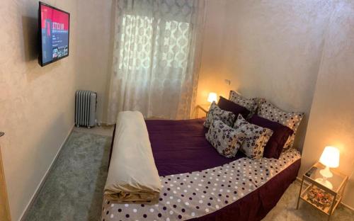 a bedroom with a large bed with pillows and a tv at Yasmine in El Jadida