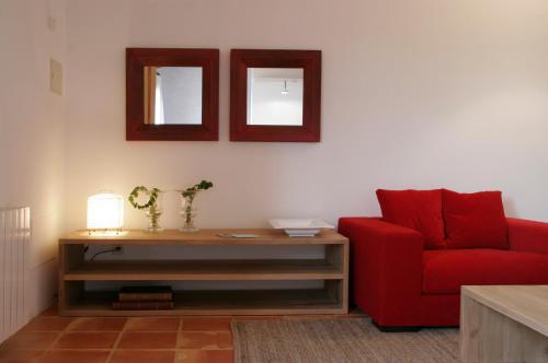 a living room with a red chair and two mirrors at Aldea Roqueta Hotel Rural in Els Ibarsos