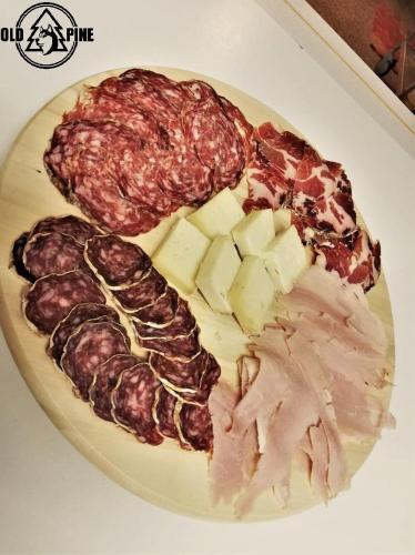 un piatto di cibo con carne e formaggio sopra di Old Pine Husky Lodge a Sompujarvi