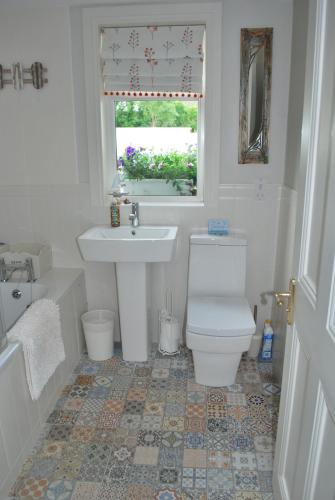 a bathroom with a toilet and a sink and a window at 5 Ellesmere Avenue in Bundoran