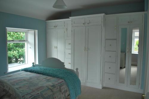 a bedroom with white cabinets and a bed and a window at 5 Ellesmere Avenue in Bundoran