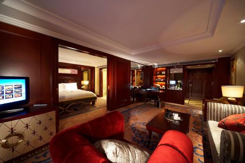 a living room with a couch and a room with a bed at Dynasty International Hotel Dalian in Jinzhou
