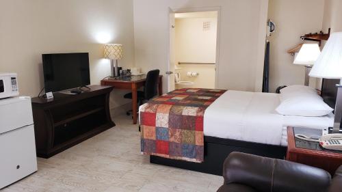 ein Hotelzimmer mit einem Bett, einem Schreibtisch und einem TV in der Unterkunft Simple Rewards Inn in Hilton Head Island