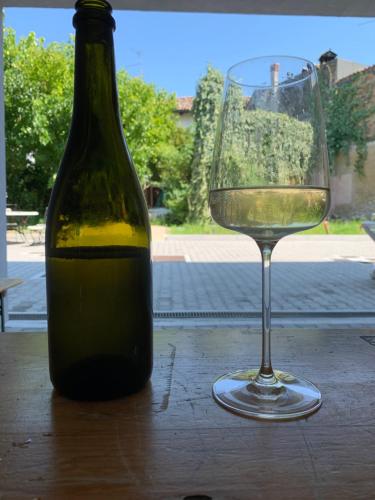 una bottiglia di vino accanto a un bicchiere su un tavolo di NAC SUITES a Porpetto