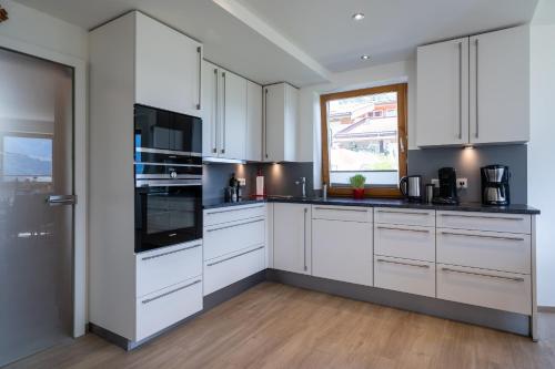 a white kitchen with white cabinets and a window at Chalet Sonnenheim in Piesendorf