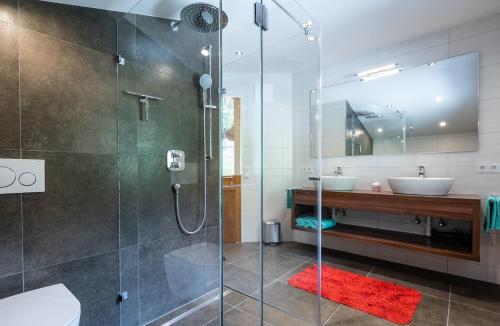 a bathroom with a glass shower and two sinks at Chalet Sonnenheim in Piesendorf