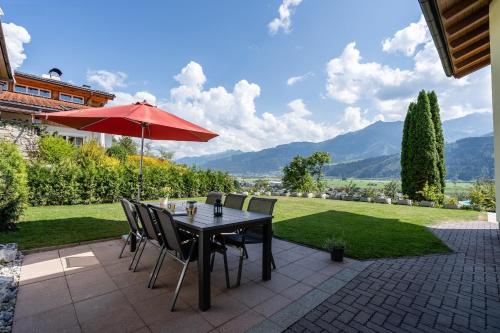 a table with chairs and an umbrella on a patio at Chalet Sonnenheim in Piesendorf