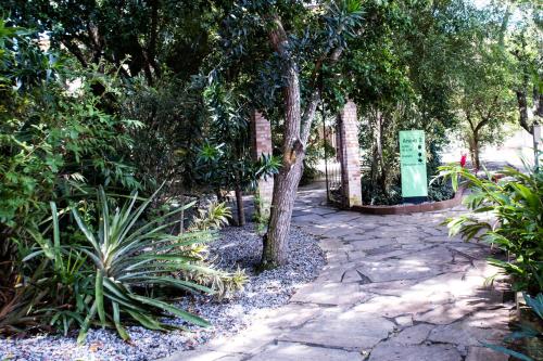 a garden with a stone walkway with trees and plants at Pousada Aguas Claras in Búzios