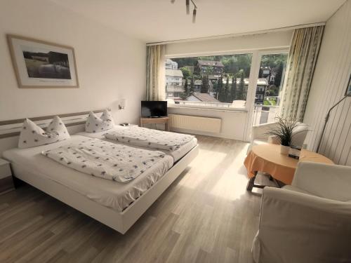 a bedroom with a bed and a table and a window at Hotel Pension Jägerstieg in Bad Grund