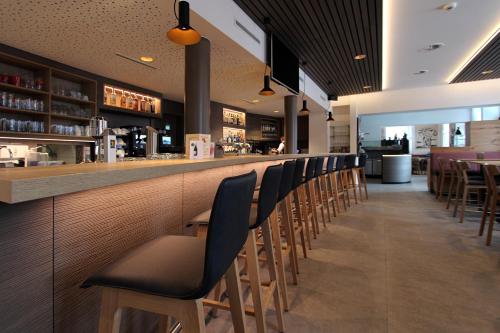 eine Bar mit einer Reihe von Stühlen in einem Restaurant in der Unterkunft Hotel Blattnerhof in Blatten bei Naters
