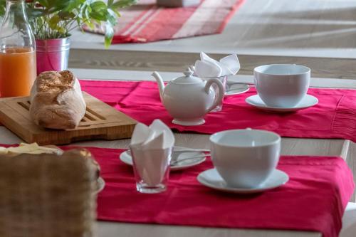 una mesa con tazas de té y platillos sobre un mantel rojo en La Vieille Maison de Pensol en Pensol
