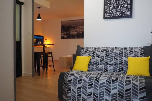 - un salon avec un canapé et 2 oreillers jaunes dans l'établissement Le Faubourg-Raines - Chaleureux studio à 5mn de la gare, à Dijon