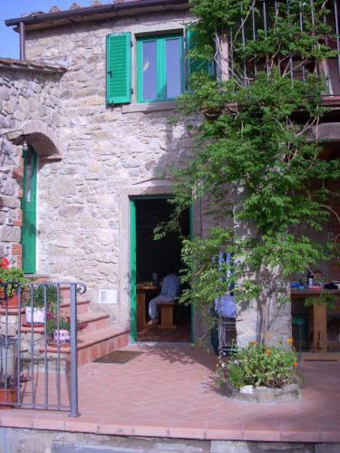 a building with a green door and a person sitting in the doorway at All'Antico Silbule in Capolona