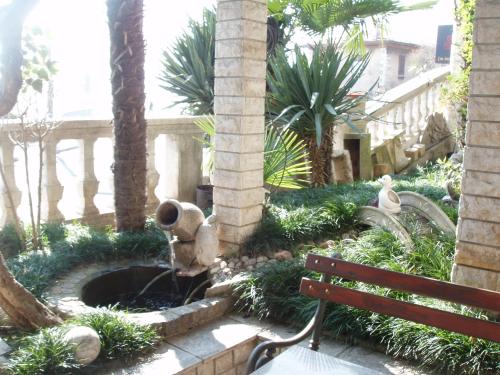 una fuente en un jardín con un banco y palmeras en Apartment Mira, en Rijeka