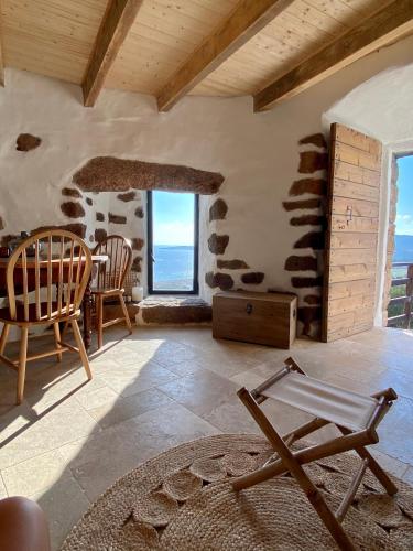 un salon avec une table, des chaises et des fenêtres dans l'établissement Tour Génoise Micalona, Domaine de l'Oglisatru, à Olmeto