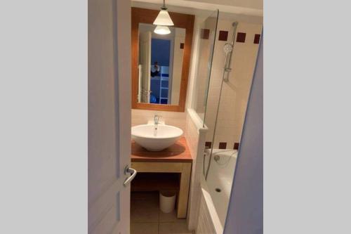 a bathroom with a sink and a mirror and a tub at Studio lumineux idéalement situé (golf et plage). in Moliets-et-Maa