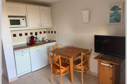 une cuisine avec une table et des chaises ainsi qu'une télévision dans l'établissement Studio lumineux idéalement situé (golf et plage)., à Moliets-et-Maa