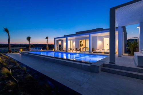 a villa with a swimming pool at night at Seashore Beachfront Villa in Lachania