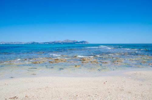 a beach with the ocean and the shoreline at Llaut Boutique Hotel in Can Picafort
